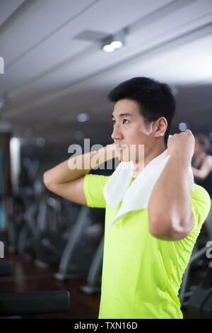 Schönen asiatischen Jungen mit weißen Handtuch im modernen Fitnessraum Stockfoto