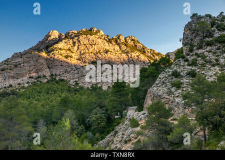 Felsen bei Sonnenaufgang über der Straße auf Area Recreativa Els Ateus an Barranc de Vall d'Uixo, Parque Natural Dels Ports, Katalonien, Spanien Stockfoto