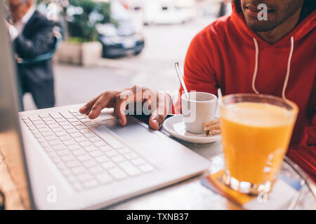 Junger Mann mit Laptop im Cafe Stockfoto