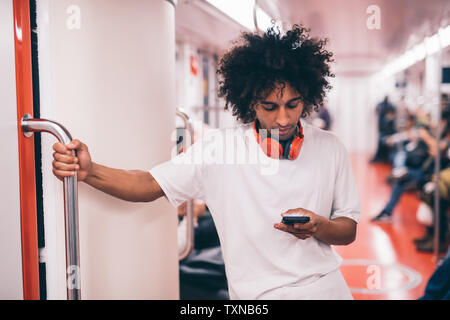 Junger Mann mit Smartphone auf Zug Stockfoto