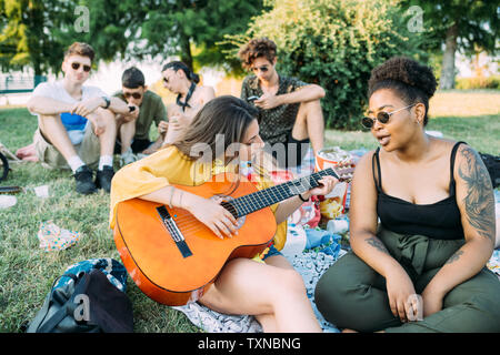 Gruppe von Freunden entspannen, Gitarre zu spielen, Picknick im Park Stockfoto