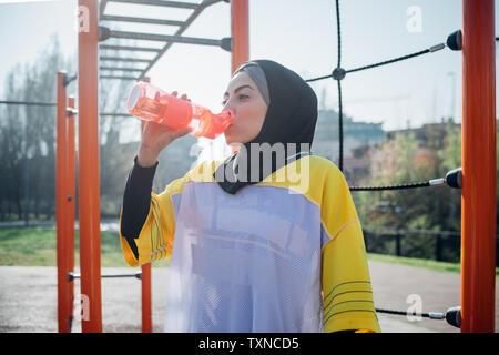Calisthenics Klasse im Fitnessbereich im Freien, junge Frau trinkt aus der Flasche Wasser Stockfoto