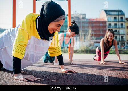 Calisthenics Klasse im Fitnessbereich im Freien, junge Frauen üben Yoga Position Stockfoto