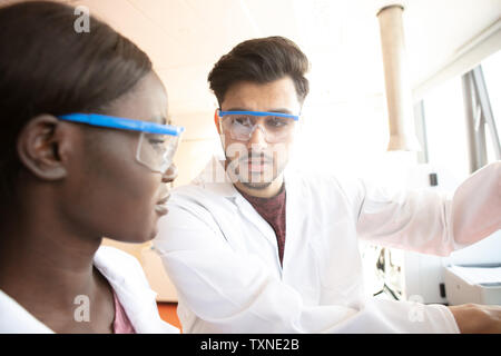 Junge weibliche und männliche Wissenschaftler Diskussion im Labor Stockfoto