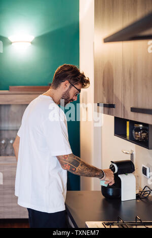 Mitte der erwachsene Mann Kaffee Gießen von Kaffeemaschine auf den Küchentisch Stockfoto