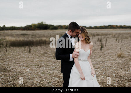 Romantische junge Paar in Feld am Hochzeitstag Stockfoto