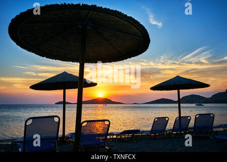 Sonnenschirme und Liegestühle bei Sonnenuntergang, Limnos, Chios, Griechenland Stockfoto