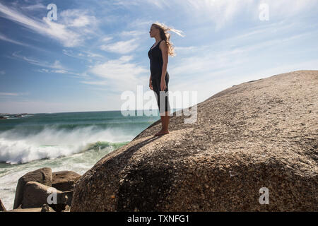 Junge Frau mit Yoga eine Pause mit Blick vom Strand Boulder, Cape Town, Western Cape, Südafrika Stockfoto