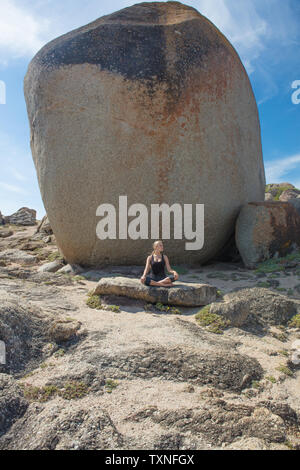 Junge Frau üben Lotus yoga Pose am Strand Felsen, Cape Town, Western Cape, Südafrika Stockfoto