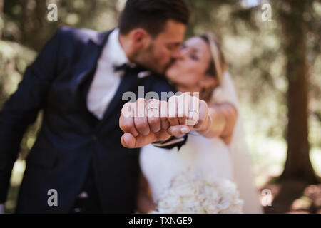Romantische Braut und Bräutigam küssen und Anzeigen Trauringe in Wäldern, selektiven Fokus auf Händen Stockfoto