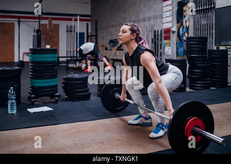 Junge Frau, die Hantel heben, im Fitness-Studio Stockfoto