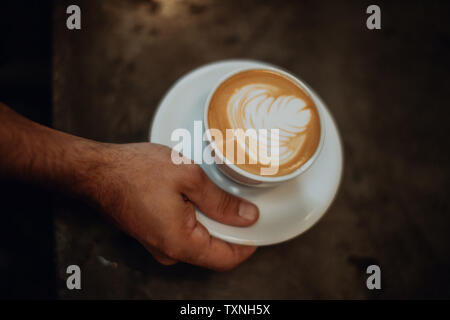 Barista Inverkehrbringen Tasse Latte auf Cafe Zähler, Overhead Nahaufnahme von Hand Stockfoto