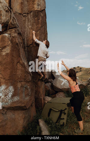 Junger Mann klettern Fels, Freundin aufpassen, Exeter, Kalifornien, USA Stockfoto
