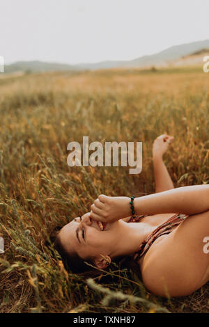 Junge Frau liegt im Bereich der langen Gras lachen, Exeter, Kalifornien, USA Stockfoto