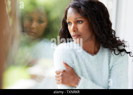 Ethnische Frau traurig saß in einem Fenster Stockfoto