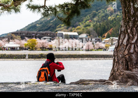 Kyoto, Japan - 11. April 2019: Arashiyama während des Tages mit Menschen tourist Sitzend durch Baum am Ufer im Frühjahr und Katsura Fluss, Bild Stockfoto