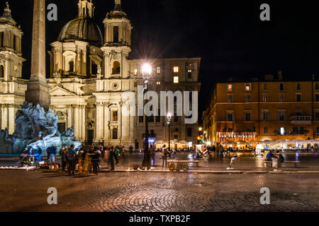 Bis spät in die Nacht auf der Piazza Navona, mit dem Brunnen der vier Flüsse und Straßencafés durch die Sant'Agnese in Agone Kirche, in Rom, Italien, beleuchtet Stockfoto