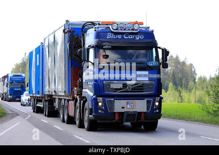 Uurainen, Finnland. Juni 7, 2019. Blaue Volvo FH 16 Lkw von Blue Cargo Oy zieht tragbare Kabinen auf Trailer im Straßenverkehr mit einem anderen Lastwagen. Stockfoto