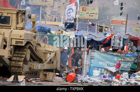 Eine ägyptische Militär bulldozer zerlegt Kairos Al-Nahda square Protest Camp nach ägyptische Sicherheitskräfte Unterstützer von Ägyptens gestürzten Präsidenten Mohamed Morsi in zwei große Lager in der ägyptischen Hauptstadt am 14 August, 2013 verteilt. Sicherheitskräfte ein Vorgehen gegen die Protest Camps, die schnell in ein Blutbad verwandelt mit Dutzenden Toten. Der Ausnahmezustand erklärt wurde. UPI/Karem Ahmed Stockfoto