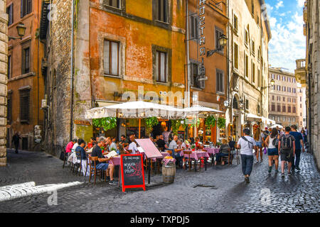 Touristen genießen Sie das Mittagessen im Sommer an einer italienischen Sidewalk Cafe Restaurant in einer Gasse in der Nähe des historischen Zentrums von Rom, Italien. Stockfoto