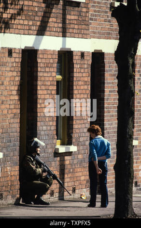 Nordirland. Belfast während der Unruhen im Jahre 1985. Junger Mann Gespräche mit der britischen Armee Soldaten auf den Straßen von West Belfast während der Troubles. Stockfoto