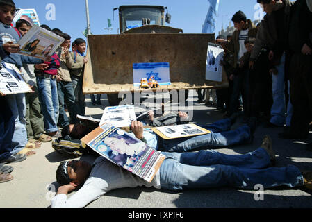 Palästinensische Kinder holding Zeichen und Bilder von Rachel Corrie vor einen Bulldozer legen während einer Demonstration den zweiten Jahrestag der Tötung im Flüchtlingslager Rafah im südlichen Gazastreifen Am 17. März 2005. Die Familie von Corrie, eine US-Aktivist von einem Bulldozer getötet, wenn Sie versuchen, den Abriss eines Palästinensischen home zu verhindern, planen einen Prozeß für widerrechtlichen Tod in eine Datei. (UPI Foto/Ismael Mohamad) Stockfoto