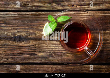 Glas Becher mit Tee, Minze und Zitrone auf Holz rustikale Hintergrund. Ansicht von oben mit der Kopie. Stockfoto