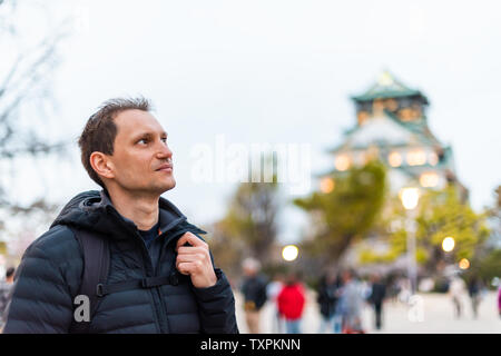 Osaka, Japan Schlosspark in Abend mit Menschen man Touristen durch Gebäude bei Nacht bokeh Hintergrund stehend Stockfoto