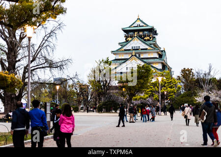 Osaka, Japan - 13. April 2019: Schlosspark in Abend mit Menschen zu Fuß durch Gebäude bei Nacht Stockfoto