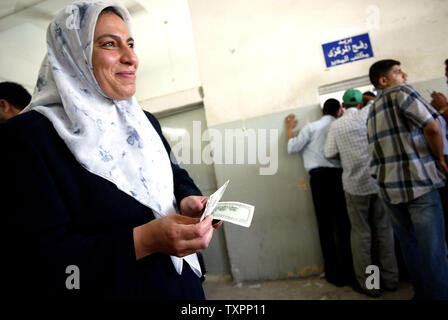 Mitarbeiter der palästinensischen Regierung Lächeln, und zeigen Sie, dass Sie Ihr Bargeld nach $ 300 US-in einem Postamt in Gaza Stadt, die am 19. Juni 2006. Tage nach dem Koffer voller Geld in den Gazastreifen, der palästinensischen Regierung heute $ 300 not Zahlungen an Tausende von verzweifelten Beamte, die nicht in fast vier Monate bezahlt wurden verteilt. Aber, in einem Zeichen von der Regierung weiterhin Schwierigkeiten, das Geld wurde durch spezielle postkonto nach lokalen Banken, aus Angst vor Verletzung der internationalen Anti-Terror-Gesetze verteilt, weigerte sich, die Bargeld zu behandeln. Stockfoto