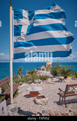 Griechische Fahne im Wind ein sonniger Tag mit Raum für Gebet und Meer im Hintergrund Stockfoto