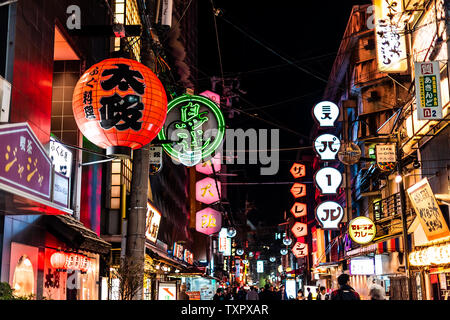 Osaka, Japan - 13. April 2019: Minami Namba berühmten Straße mit Menschen zu Fuß in dunkler Nacht und beleuchtete neon Gebäude mit roten Papierlaternen Stockfoto