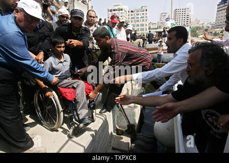 Die Palästinenser tragen ein Junge, der sein Bein an Bord eines Bootes von ausländischen Friedensaktivisten, die ihn ins Ausland für medizinische Behandlung verloren, in Gaza, Gaza am 28 August, 2008. Vor der Abfahrt des Schiffes aus dem Hafen, dem ehemaligen palästinensischen Premierminister und hochrangige Hamas-Führer Ismail Hanija hat diplomatische Palästinensischen Pässen zu 47 internationalen Friedensaktivistin, die in Zypern mit ein paar Gazas Bewohner an Bord zurück. (UPI Foto/Ismael Mohamad) Stockfoto