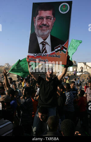 Palästinenser feiern den Sieg der Präsidentschaftskandidat der Muslimbruderschaft, Mohamed Morsi (Portrait), in der die Wahlen in Ägypten, in der Nähe der Stadt Rafah an der Grenze zu Ägypten im südlichen Gazastreifen, am 24. Juni 2012. Muslimbruderschaft Mitglied Mohamed Morsi war der erste Präsident von Ägypten erklärt seit ein Volksaufstand Hosni Mubarak verdrängt, Capping eine turbulente und Trennende militärisch-led-Übergang. UPI/Ismael Mohamad Stockfoto