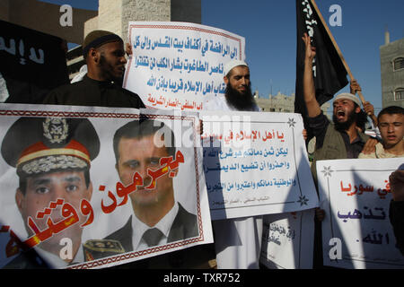 Eine palästinensische Salafistischen shouts Parolen vor einem Plakat mit Syrien Präsident Baschar al-Assad (R) und Ägyptens Armeechef General Abdel Fattah al-Sisi mit der arabischen Wörter, lesen ' Verbrecher und Mörder', während einer Kundgebung aus Protest gegen das, was sie sagen, sind die jüngsten Massaker gegen die syrische und ägyptische Volk begangen, in Rafah im südlichen Gazastreifen, 22. August 2013. UPI/Ismael Mohamad Stockfoto