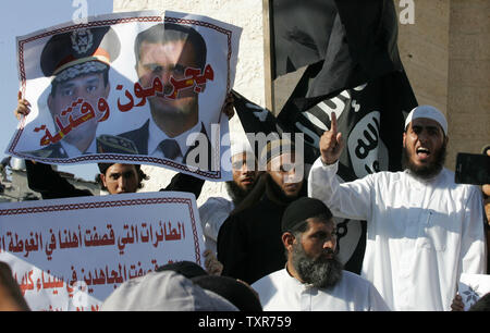 Eine palästinensische Salafistischen shouts Parolen vor einem Plakat mit Syrien Präsident Baschar al-Assad (R) und Ägyptens Armeechef General Abdel Fattah al-Sisi mit der arabischen Wörter, lesen ' Verbrecher und Mörder', während einer Kundgebung aus Protest gegen das, was sie sagen, sind die jüngsten Massaker gegen die syrische und ägyptische Volk begangen, in Rafah im südlichen Gazastreifen, 22. August 2013. UPI/Ismael Mohamad Stockfoto