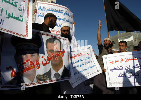 Eine palästinensische Salafistischen shouts Parolen vor einem Plakat mit Syrien Präsident Baschar al-Assad (R) und Ägyptens Armeechef General Abdel Fattah al-Sisi mit der arabischen Wörter, lesen ' Verbrecher und Mörder', während einer Kundgebung aus Protest gegen das, was sie sagen, sind die jüngsten Massaker gegen die syrische und ägyptische Volk begangen, in Rafah im südlichen Gazastreifen, 22. August 2013. UPI/Ismael Mohamad Stockfoto