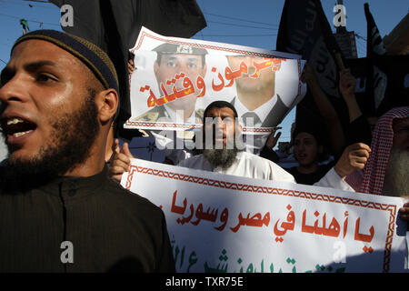 Eine palästinensische Salafistischen shouts Parolen vor einem Plakat mit Syrien Präsident Baschar al-Assad (R) und Ägyptens Armeechef General Abdel Fattah al-Sisi mit der arabischen Wörter, lesen ' Verbrecher und Mörder', während einer Kundgebung aus Protest gegen das, was sie sagen, sind die jüngsten Massaker gegen die syrische und ägyptische Volk begangen, in Rafah im südlichen Gazastreifen, 22. August 2013. UPI/Ismael Mohamad Stockfoto