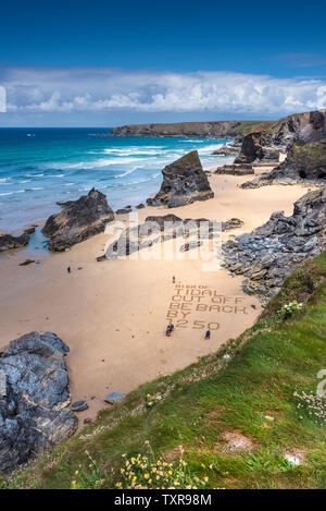 Eine Warnung in den Sand geschrieben am Strand an der robusten, spektakuläre Bedruthan Steps auf der nördlichen Küste von Cornwall. Stockfoto