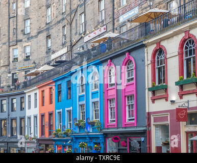 Die Fassaden der alten Häuser aus Stein, mit Leuten auf Victoria Terrasse über dem farbenfrohen Läden in der Altstadt von Victoria Street, Edinburgh Old Town. Stockfoto