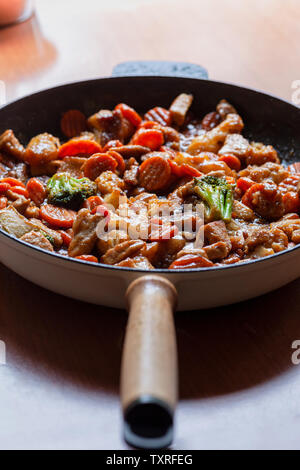 Hot gusseisernen Pfanne mit frischen Braten mit verschiedenen Gemüse- und Fleischstücke durchrühren Stockfoto