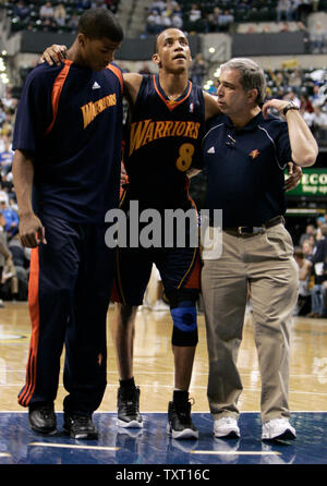 Golden State Warriors Schutz Monta Ellis (8) ist nicht der Hof durch Mannschaftskameraden Kelenna Azubuike, Links, und Trainer Tom Abdenour nach seinem linken Knie verletzt während der zweiten Hälfte gegen die Indiana Pacers bei Conseco Fieldhouse in Indianapolis, 5. Februar 2007. Golden State besiegt die Schrittmacher 113-98. Röntgenstrahlen von Ellis' Knie waren negativ für schwere Verletzungen. (UPI Foto/Markierung Cowan) Stockfoto