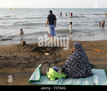 Eine verschleierte iranische Frau sitzt am Strand des Kaspischen Meeres, in Babolsar, Provinz Mazandaran im Iran Am 15. Juli 2011. Muslimische Frauen im Iran sind nicht erlaubt in einem öffentlichen Plätzen zu schwimmen. UPI/Maryam Rahmanian Stockfoto