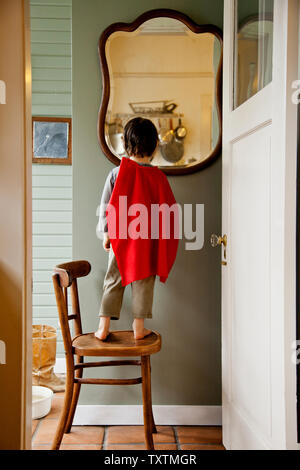 Junge trägt ein superhero Cape im Spiegel zu betrachten. Stockfoto