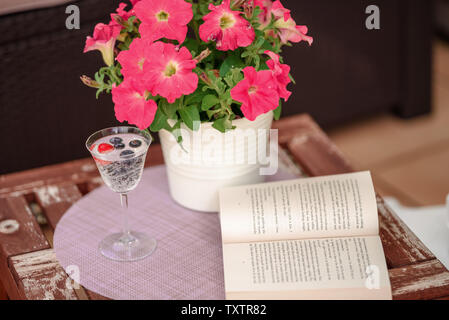 Schöne gemütliche Komposition mit Tasse Kaffee, Blumen und alten Buch auf Holztisch. Frühling, Sommer Saison. Zarte Feder romantische Szene. Stockfoto