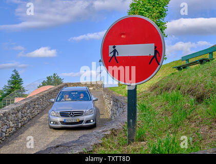 Auto fährt durch No Entry Verkehrsschild, geändert durch das Hinzufügen von menschlichen Form Aufkleber, um aussehen zu lassen, als ob die weiße Linie tragen Stockfoto