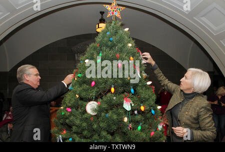 Missouri Gouverneur Jay Nixon und First Lady Georganne Nixon Arbeit Ornamente auf der offiziellen Weihnachtsbaum dekorieren während einer Zeremonie im State Capitol Building in Jefferson City, Missouri, am 3. Dezember 2010 statt. Kindergartner's aus dem nahe gelegenen Ceder Hill Volksschule half der Gouverneur schmücken die 8-Fuß, Scotch pine Tree. UPI/Rechnung Greenblatt Stockfoto