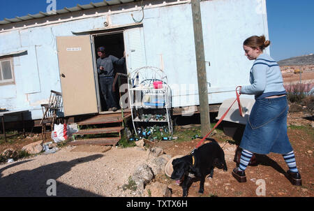 Ein nicht identifiziertes Israelischen geht ein Hund vor dem Wohnwagen in der unerlaubter Vorposten Siedlung Ginot Aryeh, in der Nähe von Ofra, 31. Dezember 2003. Bewohner von ginot Aryeh offizielle Vertreibung Nachrichten am Dienstag von der israelischen Regierung als Teil eines Planes, vier Outpost Siedlungen in der West Bank zu demontieren. (UPI Foto/Debbie Hill) Stockfoto