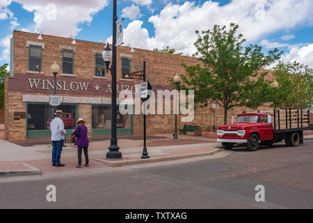 Winslow Arizona, USA 5/16/2016. Zwei Personen stehen auf der Ecke. Seite von Gebäude mit Kunst arbeiten, Windows, Menschen umarmen, Adler, LKW-Pritsche Ford Stockfoto