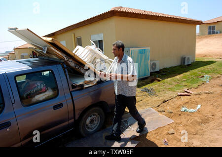 Israelischer Siedler aus Nisanit Edre Sinai in den Gazastreifen entlädt persönliche Sachen von seinem Lkw in der Nähe ein neues Mobilheim in Nitzan, im Süden Israels, 1. August 2005. Sinai ist der Wechsel in die vorübergehende Unterbringung für die israelischen Siedler, die vor der bevorstehenden Rückzug aus dem Gazastreifen zu bewegen möchten. Der israelische Premierminister Ariel Sharon sagte, dass über die Hälfte der in Frage kommenden Bewohner des Gazastreifens ausgefüllt haben Anwendungen, eine Entschädigung vom Rückzug Behörde zu erhalten. (UPI Foto/Debbie Hill) Stockfoto